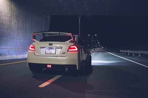 Sport car with red taillights driving under bridge