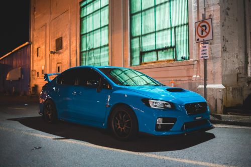 Free Contemporary blue automobile parked near aged weathered building with large windows in late evening Stock Photo