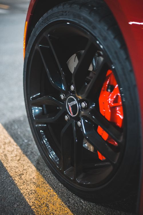 Free From above of wheel of modern red auto parked on concrete surface of parking lot Stock Photo