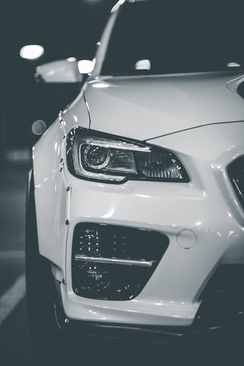 White colored luxury car with shiny headlights and glossy bumper parked at parking lot