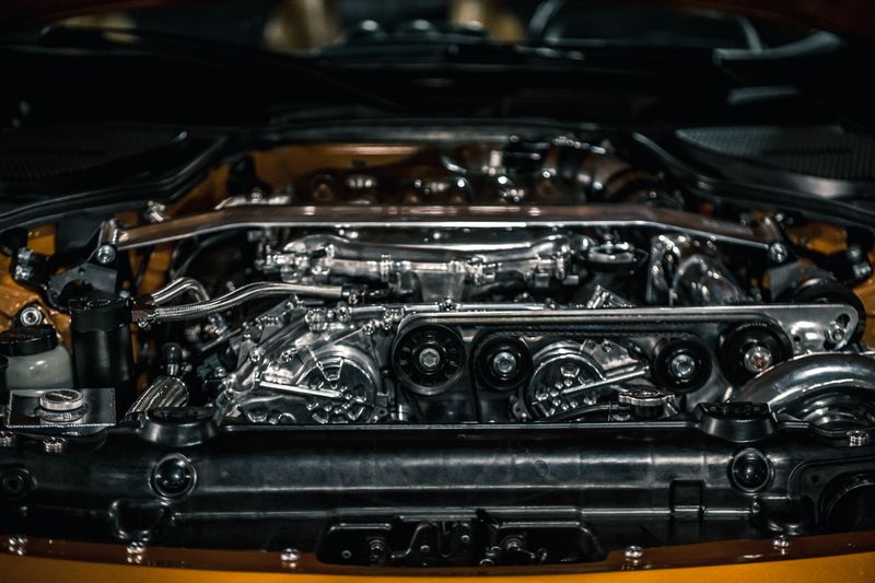 From above of polished stainless engine and automobile apparatuses under hood of new car