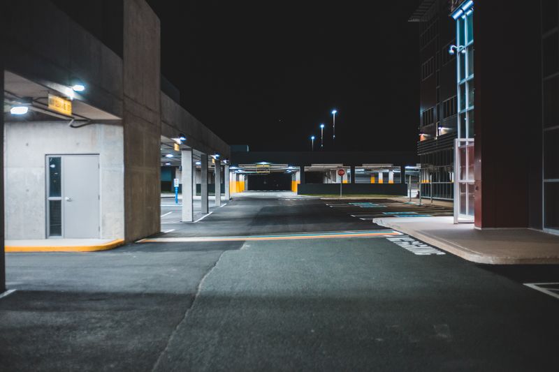 Lit parking lot at night beside a commercial building