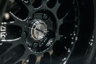 Small round glistening center cap with inscription on disk of modern car wheel with spokes
