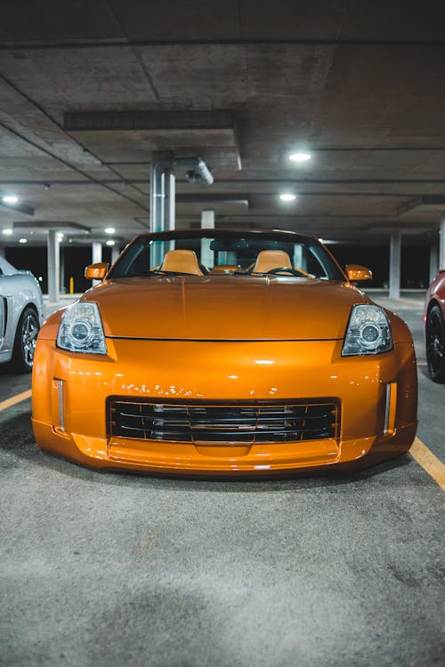 New expensive prestige orange automobile on asphalt road under concrete roof with bright illumination