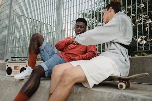 Ernsthafte Schwarze Mannfaust, Die Mit Männlichem Freund Stößt, Der Auf Skateboard Sitzt