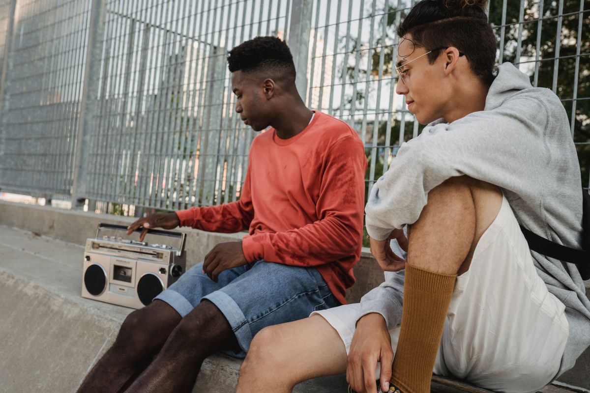 A diverse group of friends gathered around a retro record player in a park, smiling