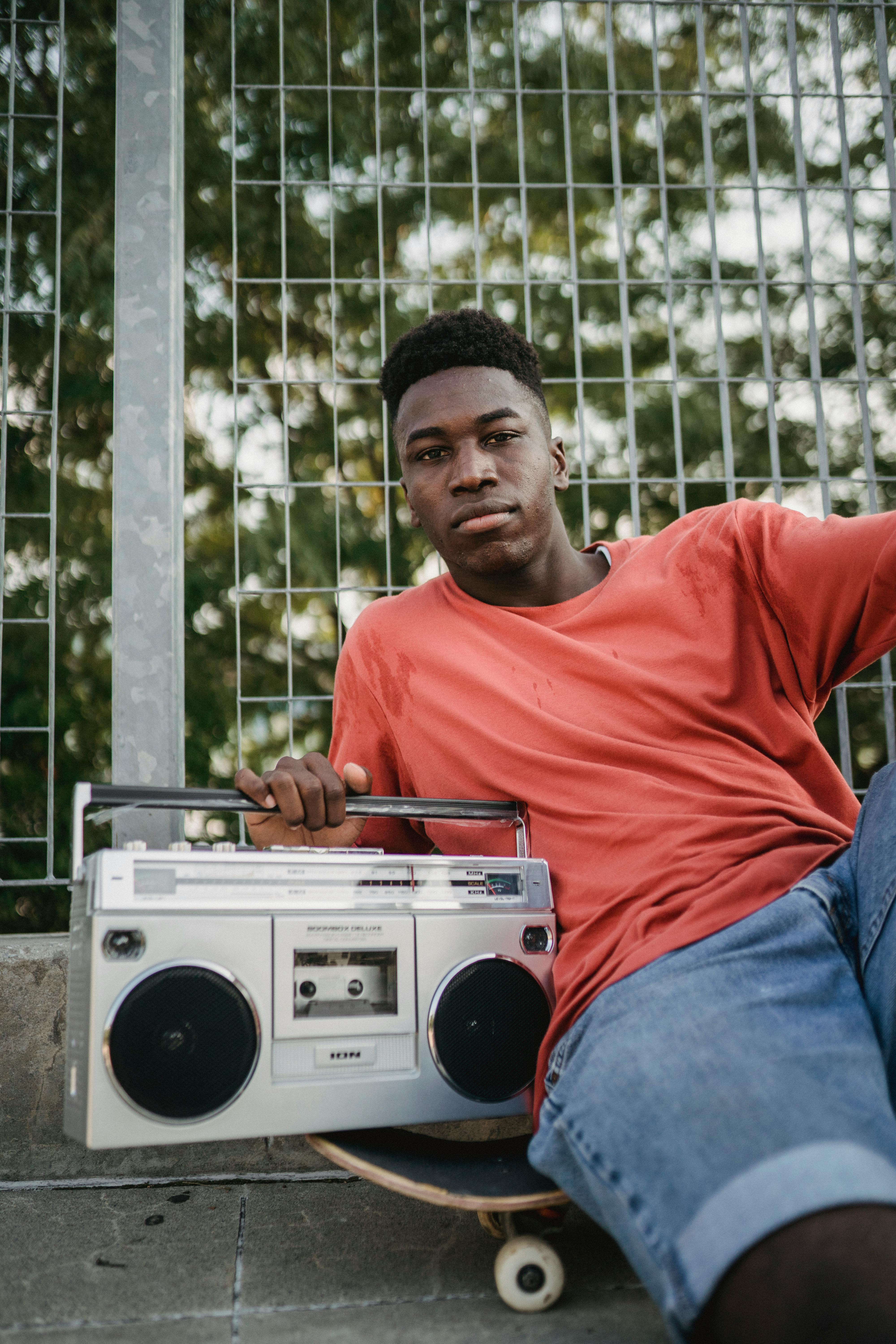 cool black sportsman with retro tape recorder on city street