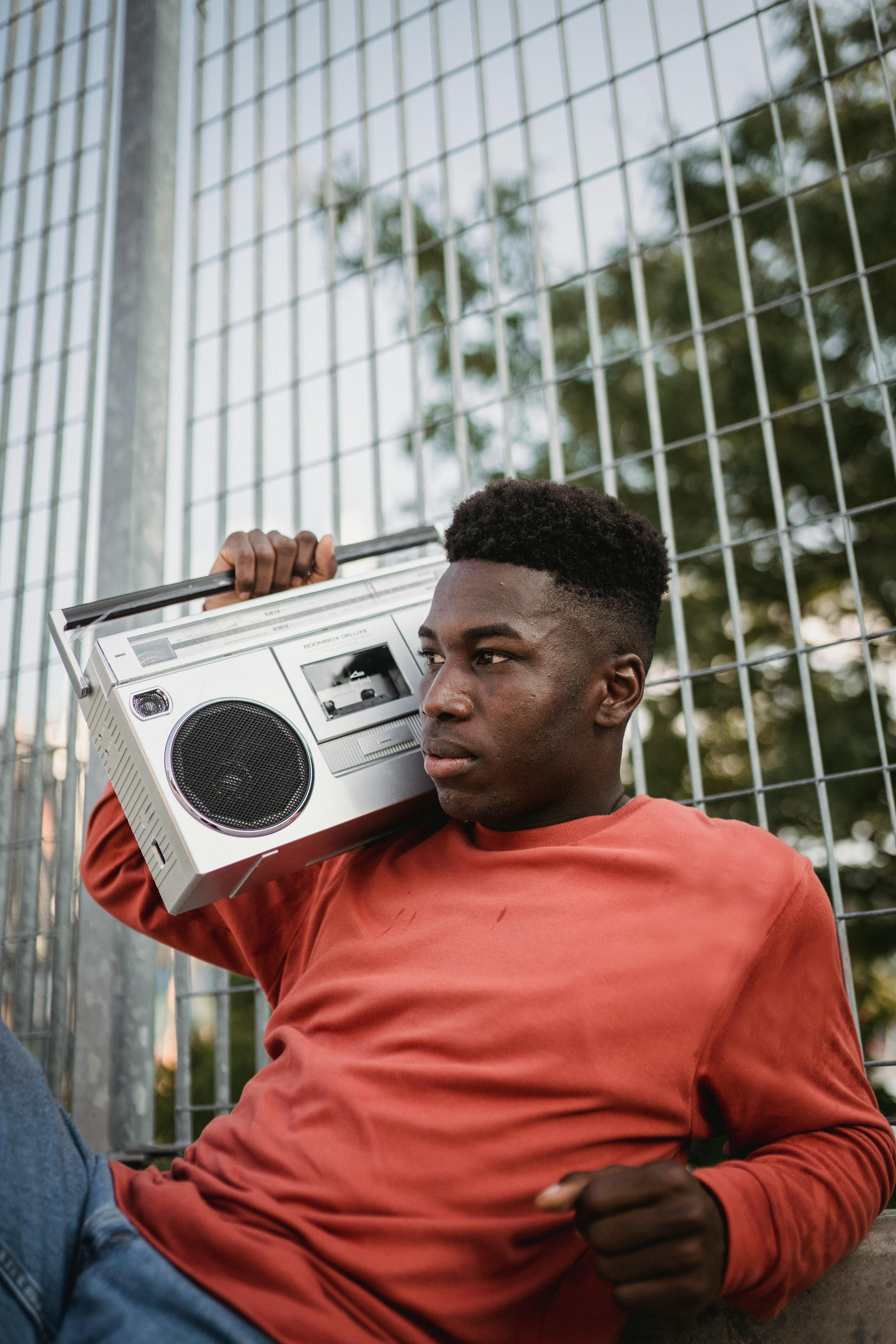 wistful black man listening to radio from vintage tape recorder