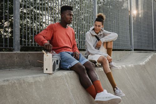 Free Young multiethnic male friends listening to song on retro cassette recorder while resting on skate ramp in town Stock Photo