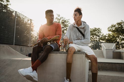 Diverse skateboarders talking on skate ramp in evening