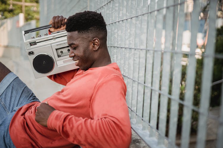 Smiling Black Man Enjoying Music From Old Tape Recorder Outdoors