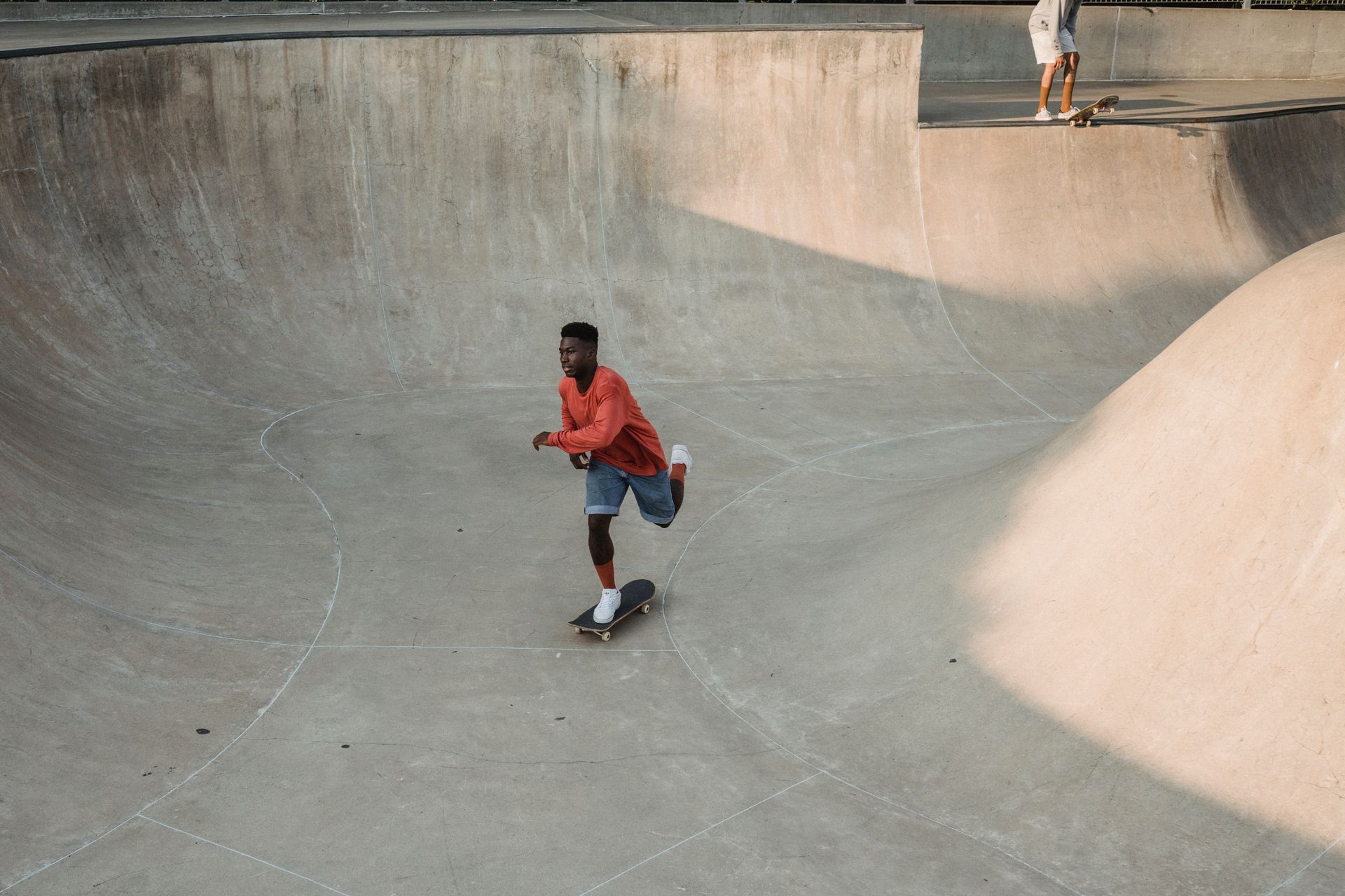 Black skateboarder practicing extreme sport near crop friend on ramp