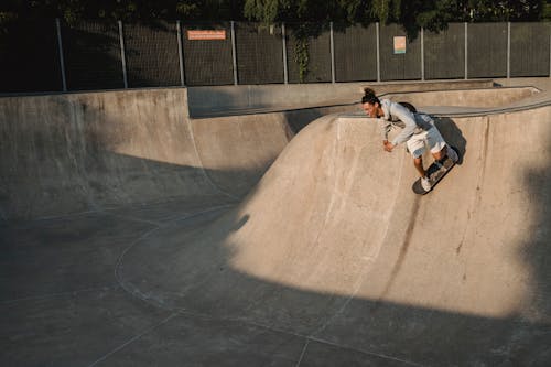 Slim male athlete balancing on skateboard while practicing extreme sport on platform in urban skate park