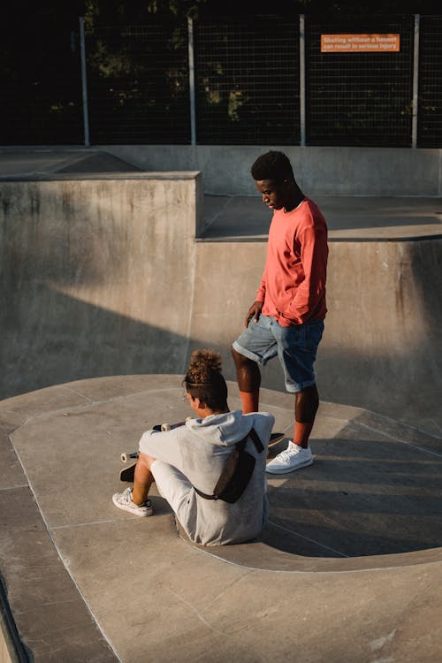 Anonymous multiracial sportsmen with skateboards interacting on city ramp