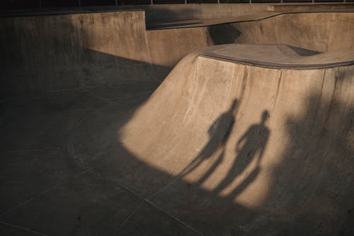 Silhouettes of unrecognizable sportsmen with skateboards on ramp