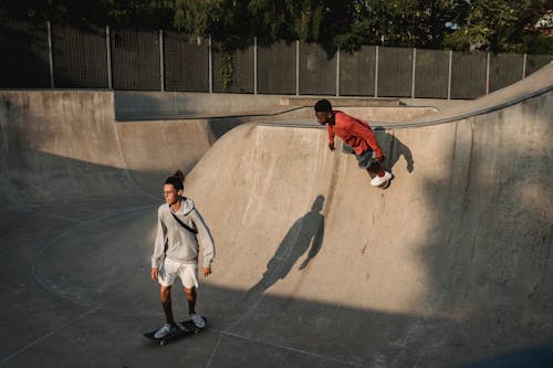 Multiethnic sportsmen skateboarding on ramp in skate park