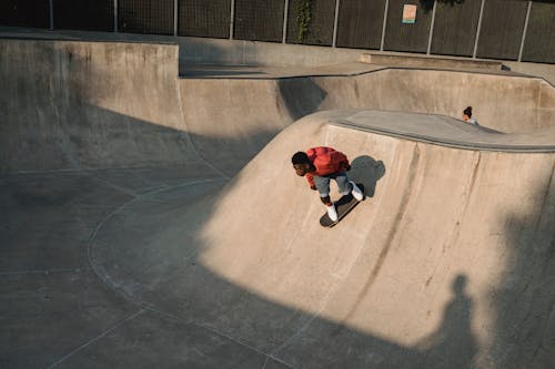 Ethnic male athlete practicing extreme sport on skateboard near anonymous partner on platform in town