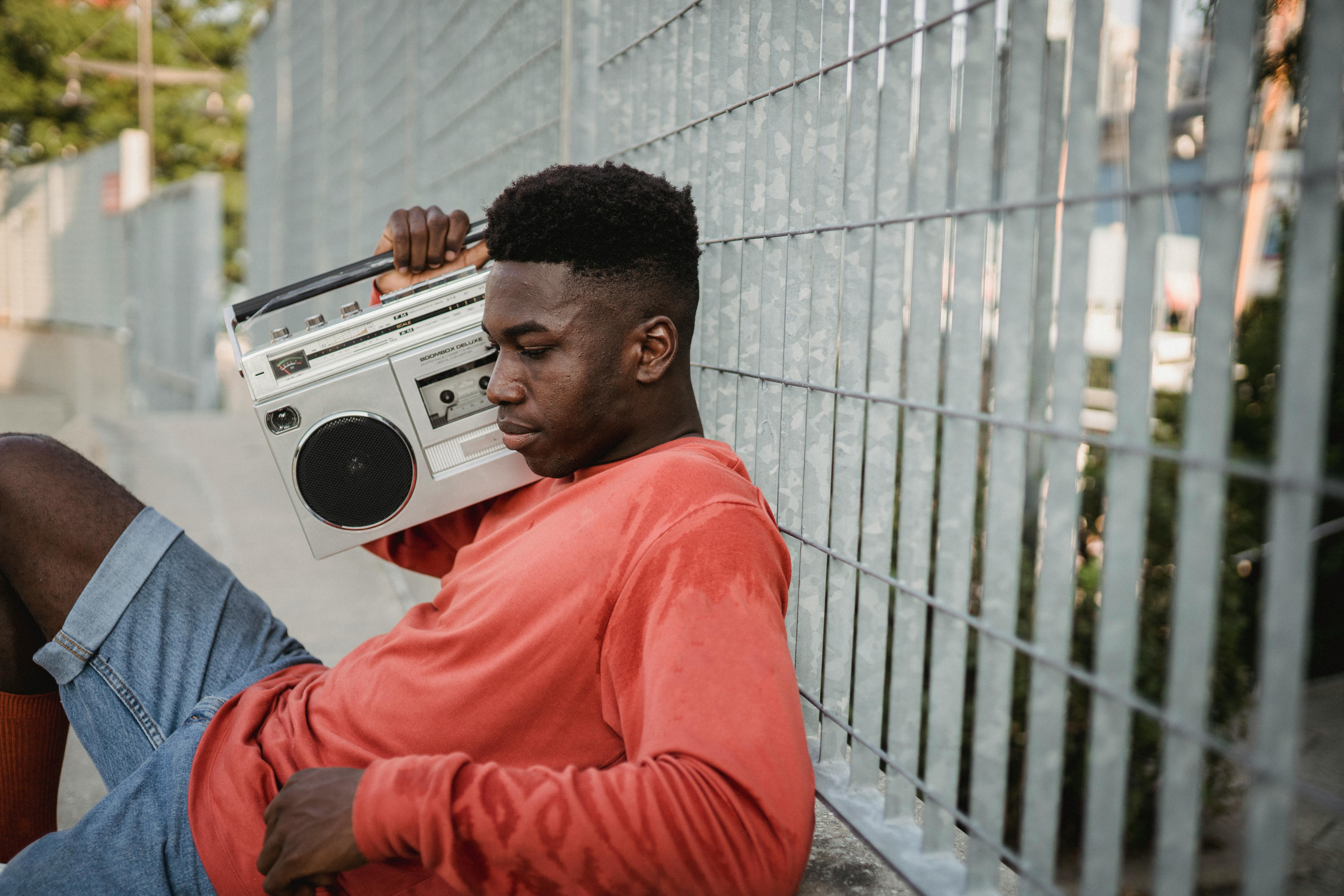 pensive black man listening to music from retro cassette recorder