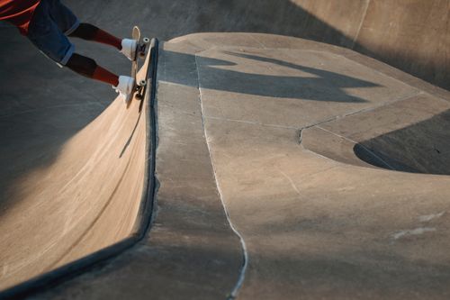 Free Crop unrecognizable male skater riding skateboard on ramp and performing trick in skate park Stock Photo