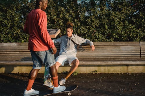 Amici Multirazziali Con Skateboard E Pizza Nel Parco