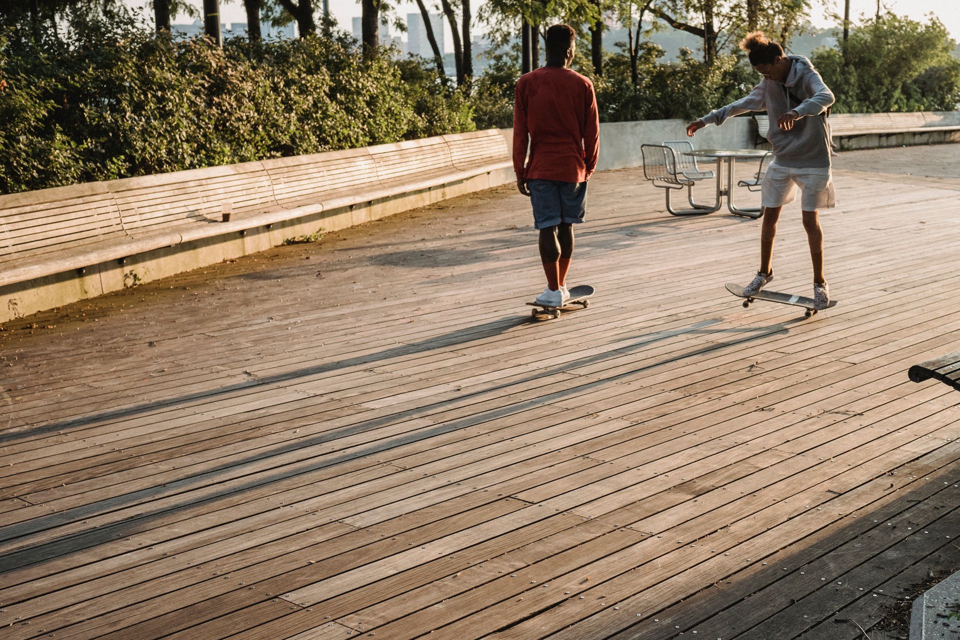 Two young men skateboarding and performing tricks on a sunny urban deck.