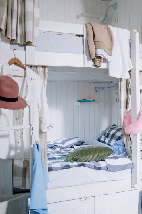 Free Neatly arranged dorm room featuring a stylish bunk bed with hanging clothes and vibrant decor. Stock Photo