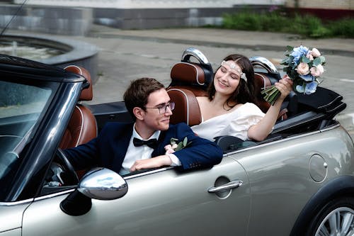 Joyful newlyweds sitting in modern cabriolet