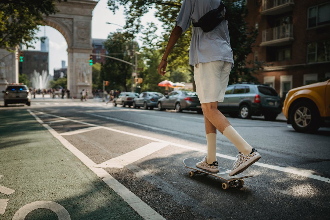 Anonymous man riding skateboard on road