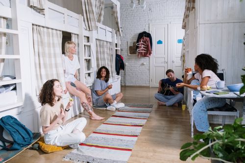 Free A diverse group of friends enjoying leisure time in a cozy shared dorm room with bunk beds. Stock Photo