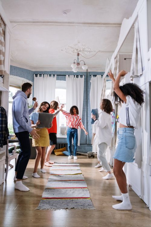 Free Group of young adults dancing together in a bright, modern room, enjoying a lively indoor party. Stock Photo