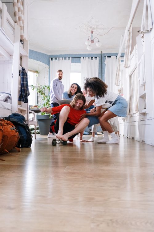 Free Group of young friends enjoying social time indoors with a skateboard. Stock Photo