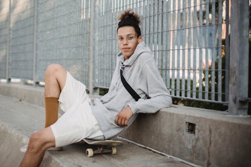 Şehir Parkı çit Yakınındaki Kaykay üzerinde Oturan Genç Etnik Adam
