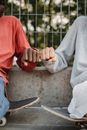 两名青少年坐在户外的滑板上，互相碰了碰拳头