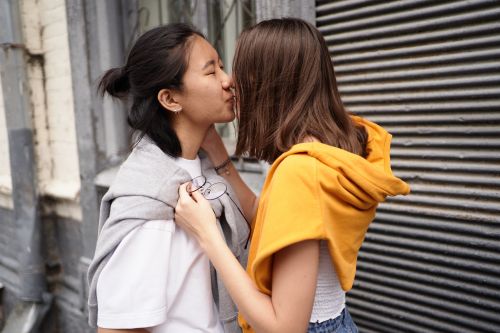 Free A young couple shares a kiss in an urban setting, expressing love and affection. Stock Photo