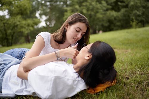 Woman in White Shirt Kissing Woman in White Shirt Lying on the Grass