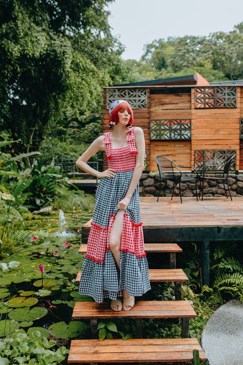 Extravagant redhead woman standing on rural cottage porch