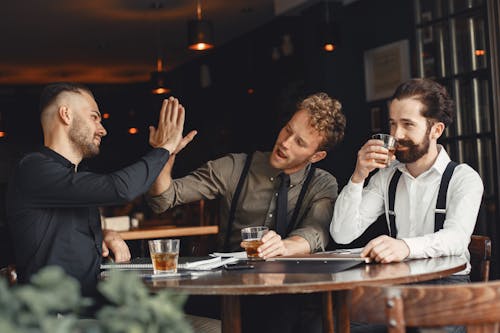 Men Doing High Five While Drinking