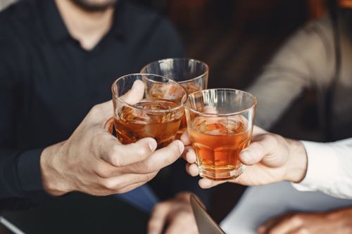 Free Three men clinking whiskey glasses in a celebration indoors, capturing camaraderie and joy. Stock Photo