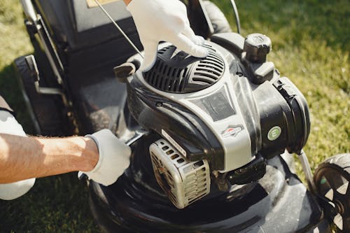Person Holding Black and Gray Lawn Mower