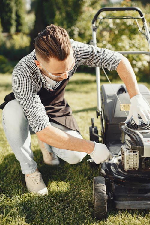 Man in Black and White Checkered Shirt Reparing the Grass Cutter
