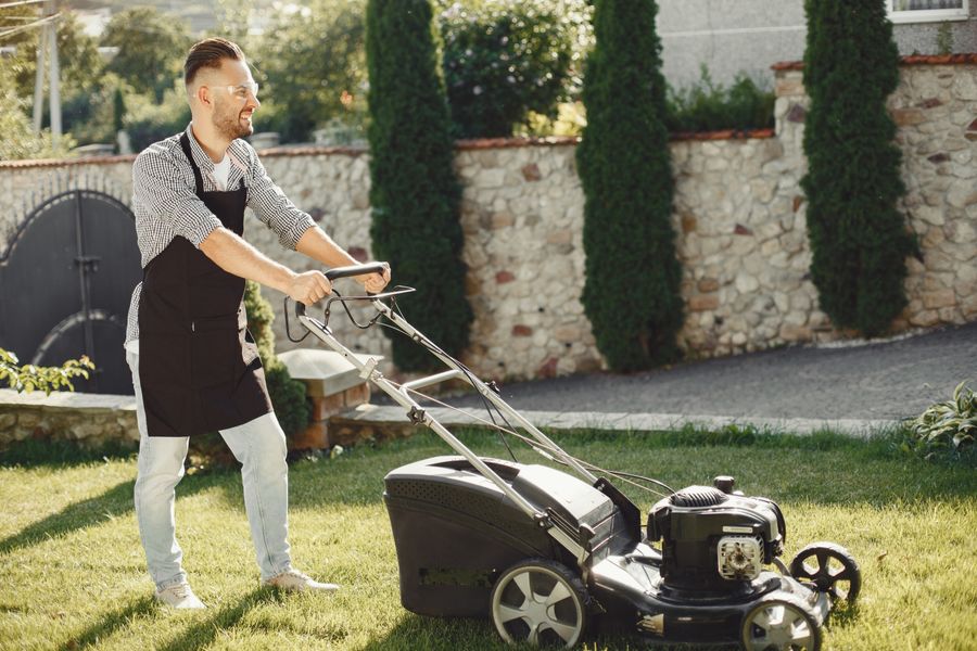 Smiling lawn care crew member mowing a residential lawn with a professional mower