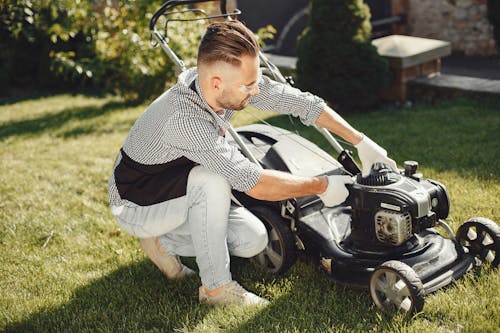 Free Man in Black and White Long Sleeve Shirt Holding Black Lawn Mower Stock Photo