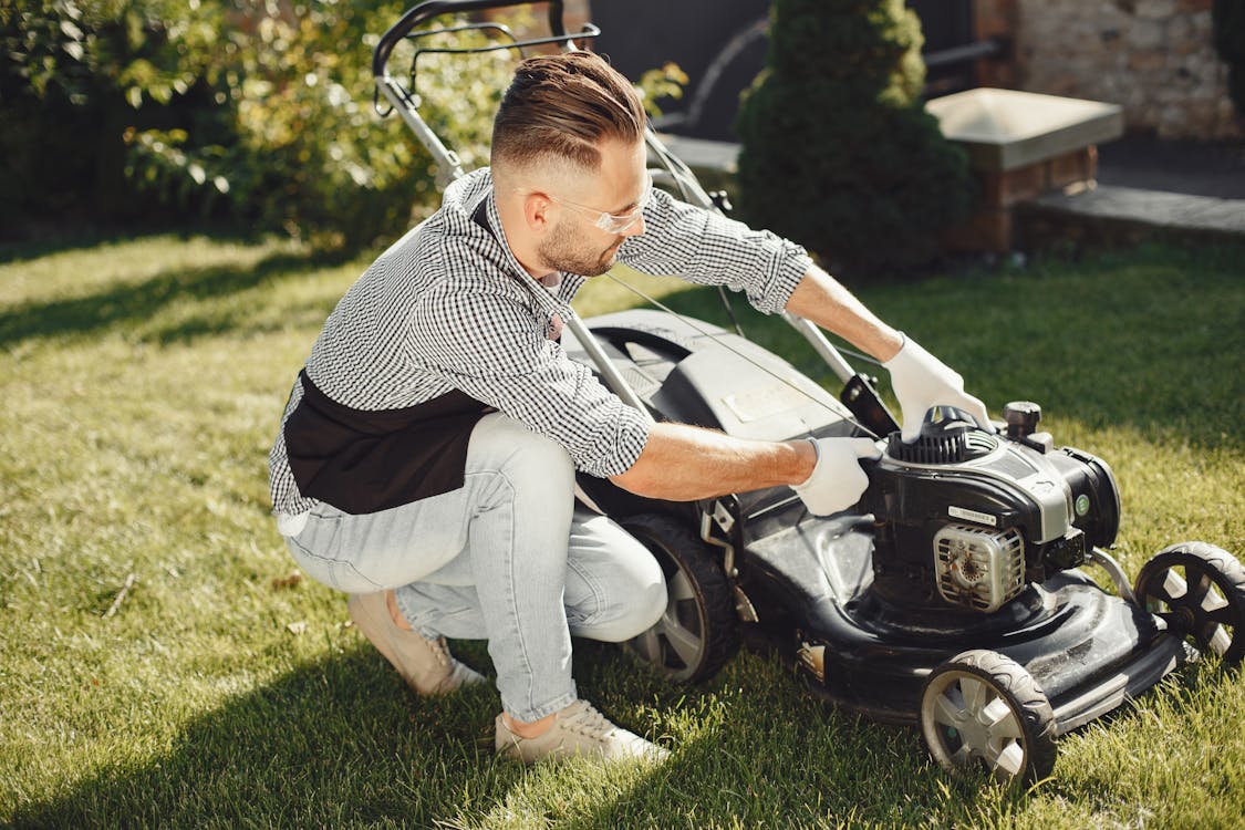 Free Man in Black and White Long Sleeve Shirt Holding Black Lawn Mower Stock Photo
