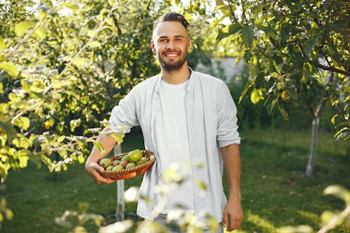 Man in White Long Sleeve Shirt Standing near Green Trees