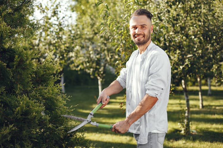 Man In Gray Long Sleeve Shirt Cutting Trees