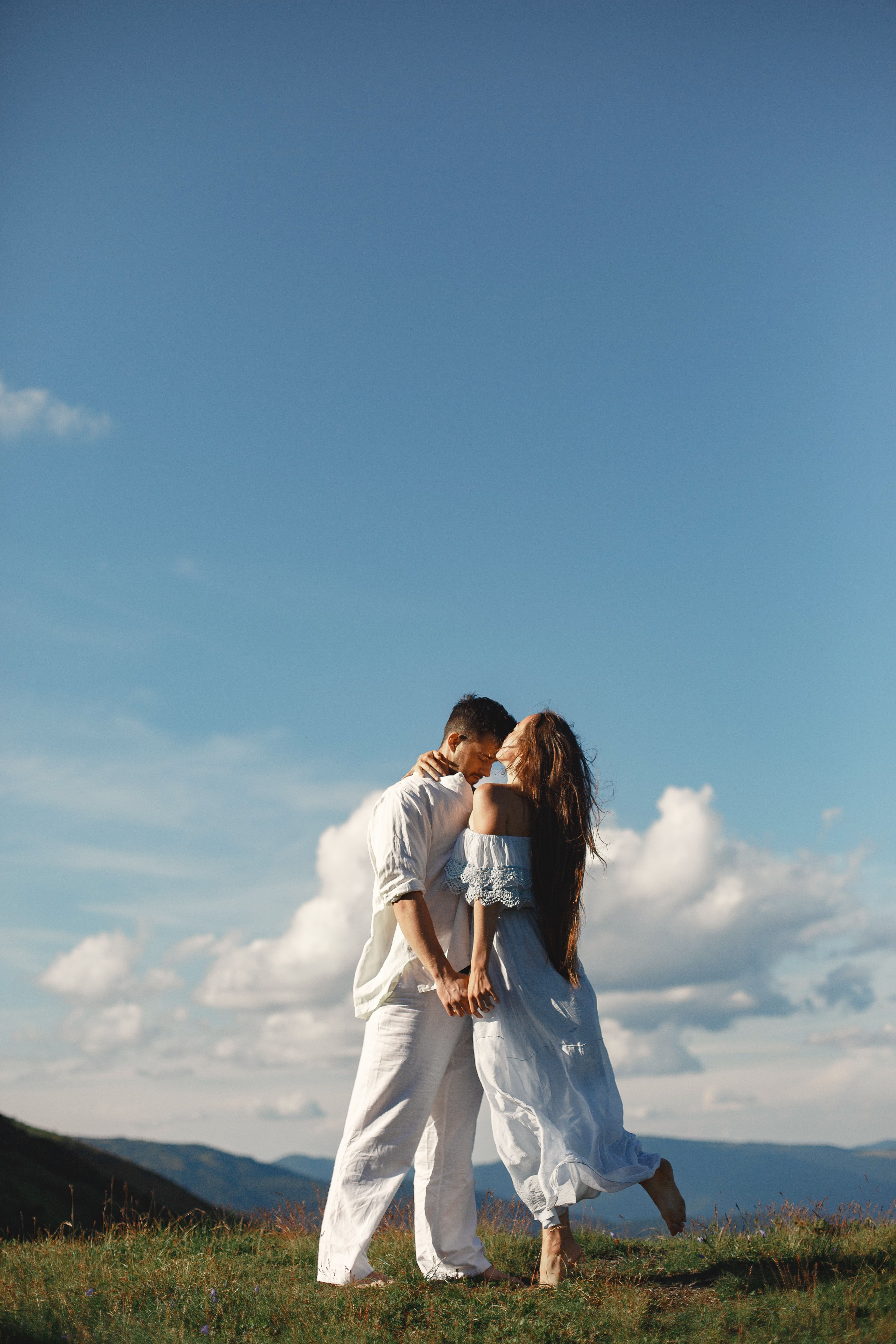 Young Couple Hugging against Blue Sky · Free Stock Photo