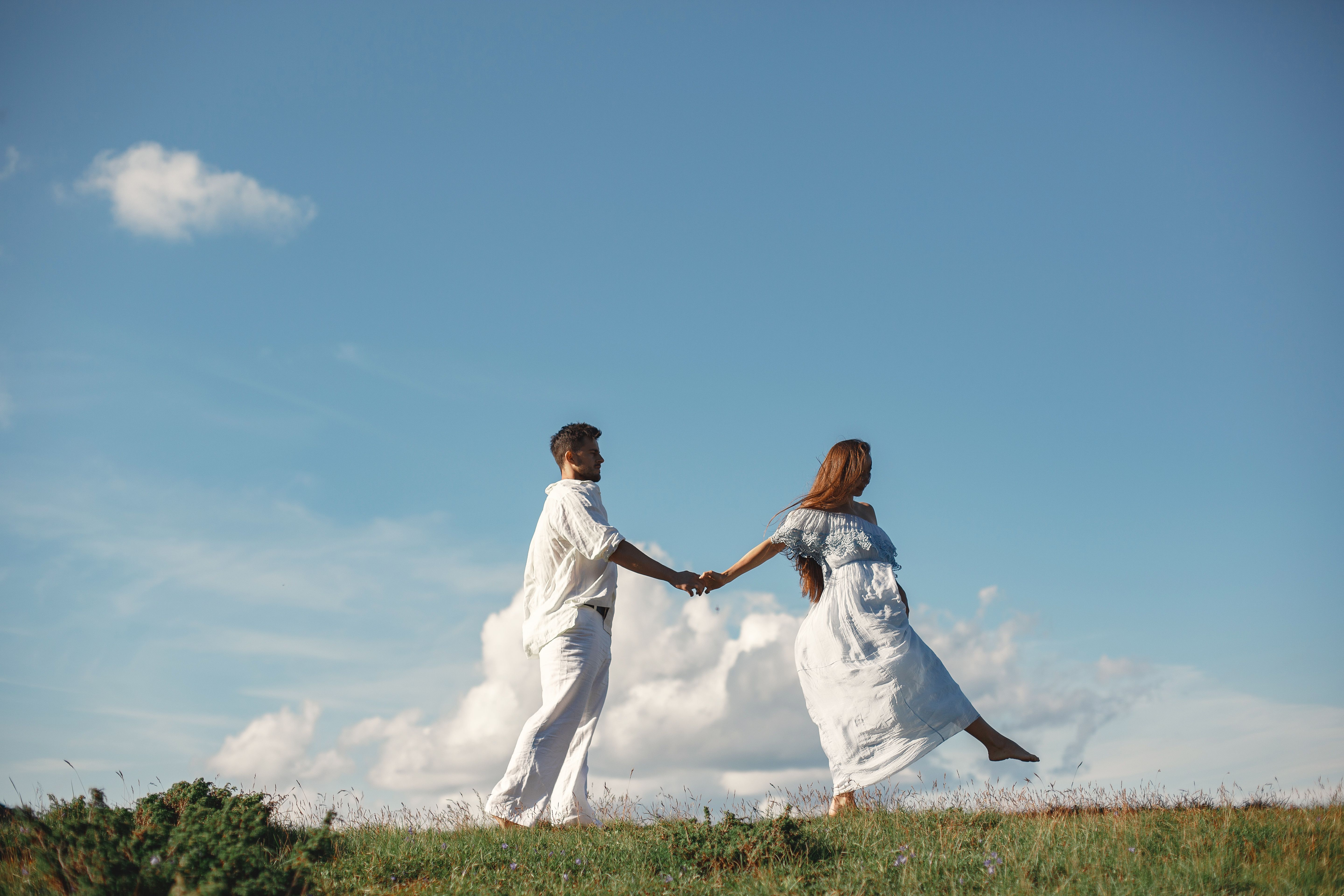 Couple Holding Hands against a Cloudy Sky · Free Stock Photo