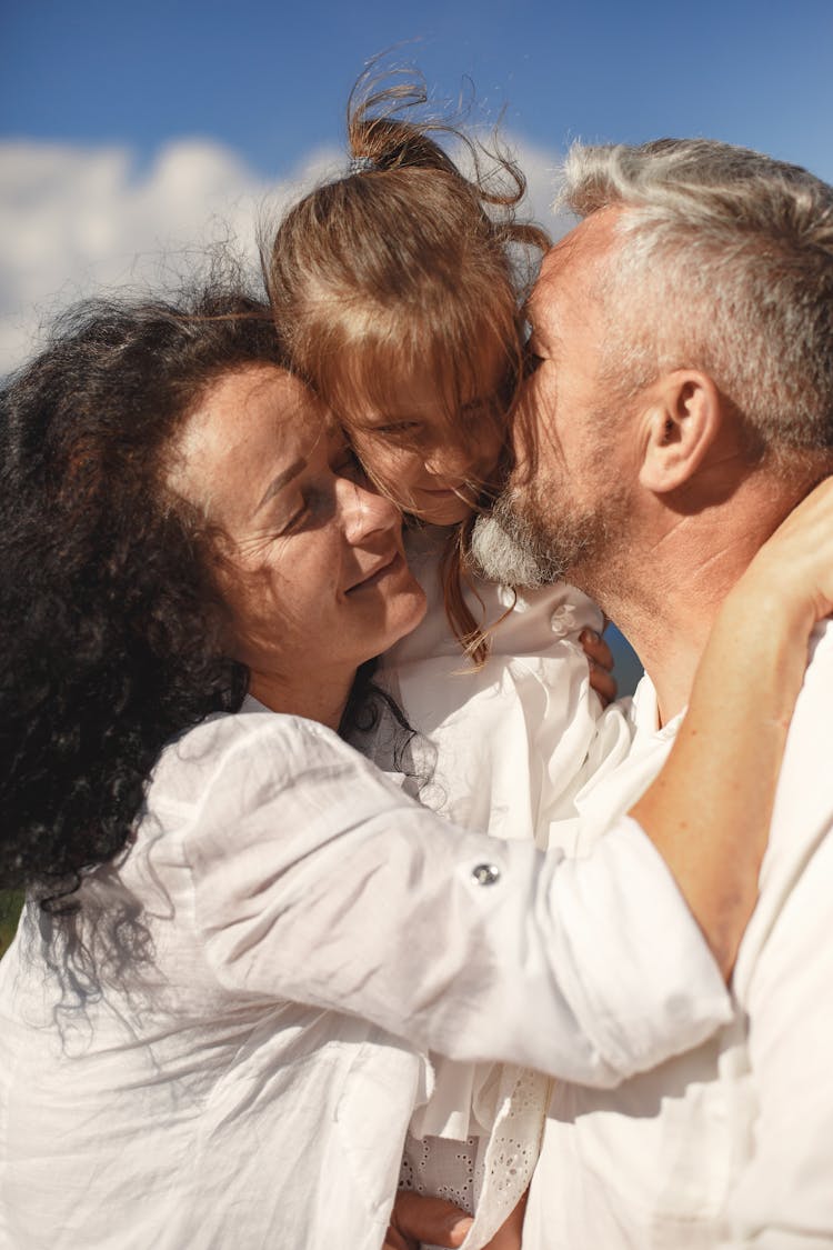 Grandparents Hugging And Kissing Their Granddaughter