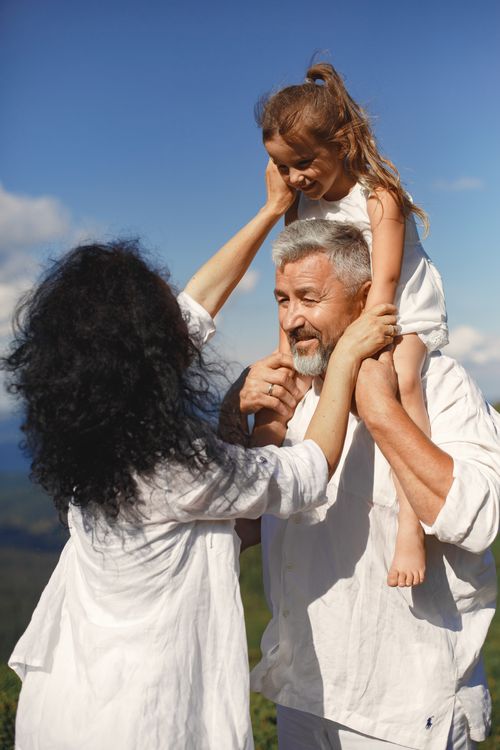 Free Grandparents playing with granddaughter outdoors, enjoying sunny day Stock Photo