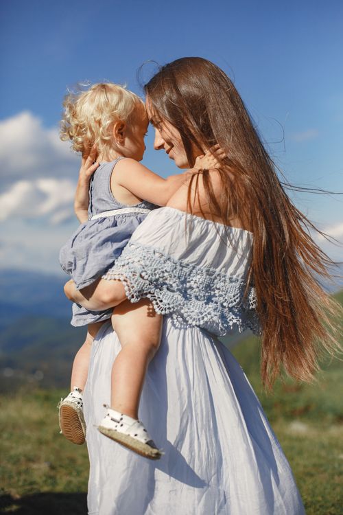 Free A mother and daughter share a loving embrace outdoors under a clear sky. Stock Photo